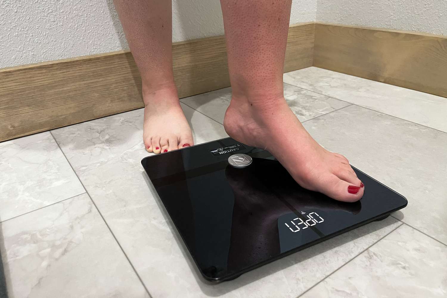 Person stepping on the Fitindex WiFi Bluetooth Body Fat Scale and other foot on tile floor